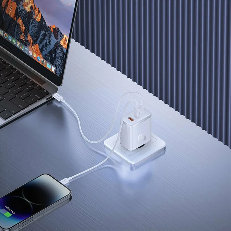 Ładowarka sieciowa Baseus 65W podłączona do gniazdka, jednocześnie ładuje laptopa i smartfon za pomocą kabli USB-C