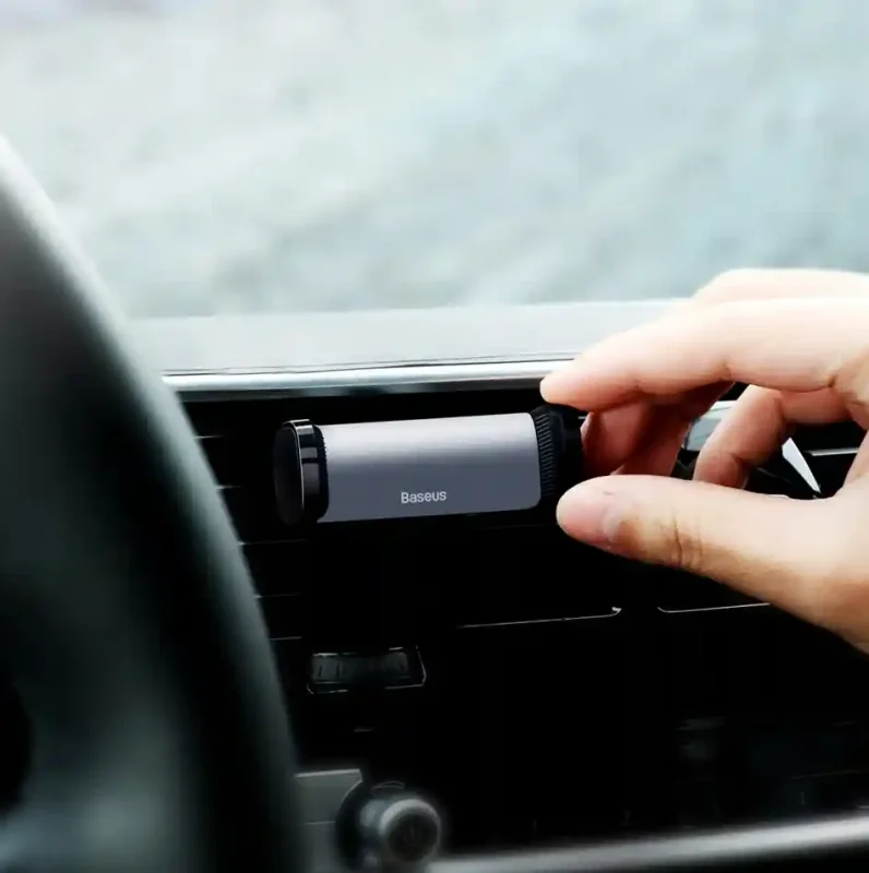 Montaż uchwytu samochodowego na kratkę klimatyzacji, ręka mocująca uchwyt na telefon w aucie