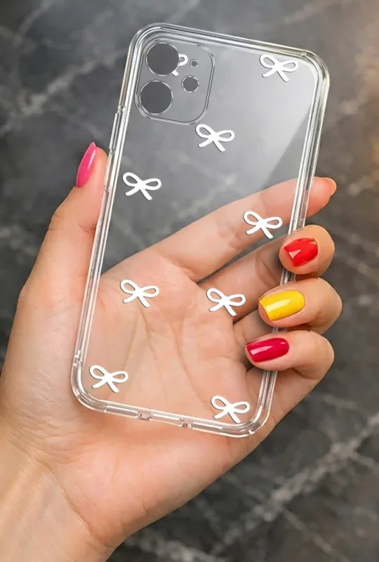 Modne etui do iPhone 11 ze stylowym wzorem białych kokardek, trzymane w dłoni