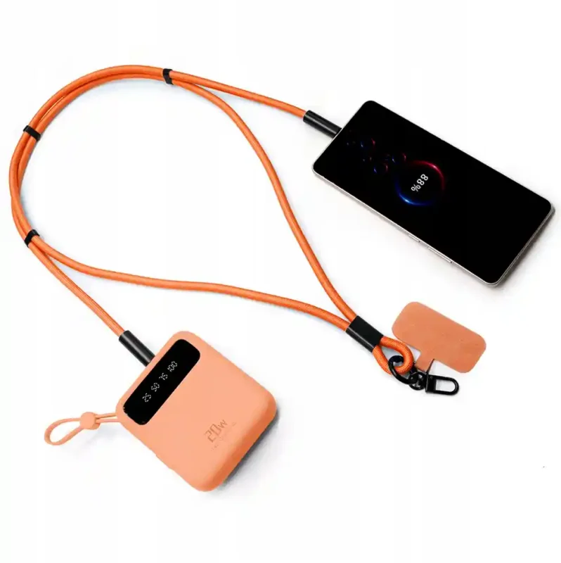 Pomarańczowa smycz z funkcją kabla USB-C podłączona do powerbanku i smartfona podczas ładowania mobilnego