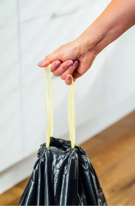 Przenoszenie zawiązanego worka Paclan Eco Line 60 l za uchwyt z taśmy