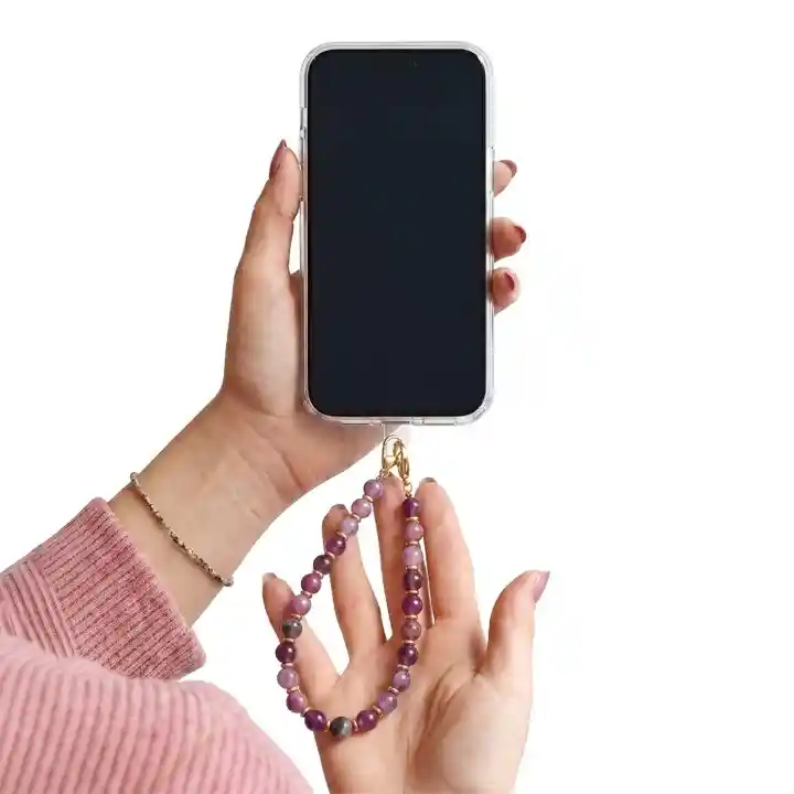 Fioletowa zawieszka do telefonu z koralikami trzymana przy smartfonie jako smycz na nadgarstek