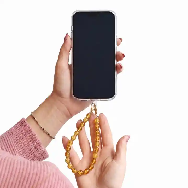 Żółta zawieszka do telefonu z koralikami trzymana przy smartfonie jako smycz na nadgarstek