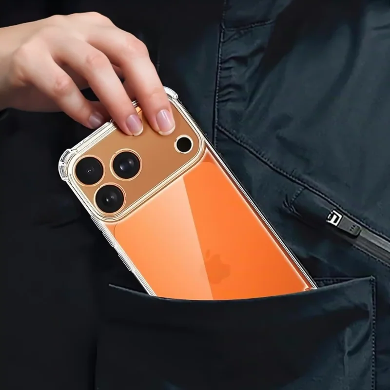 Dłoń wsuwająca pomarańczowy iPhone 17 Pro Max / 18 Pro Max w przezroczystym etui ochronnym z osłoną aparatów i wzmocnionymi narożnikami do kieszeni czarnej kurtki